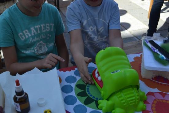 Zwei Kinder im Park beschäftigen sich spielerisch mit der Mundgesundheit von einem grünen Spielzeugkrokodil